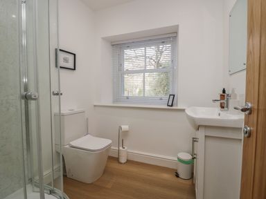 A bathroom with a shower enclosure toilet sink window with blinds and wooden floor at Dalegarth Hall Farm Cottage 1 Boot near Eskdale Green