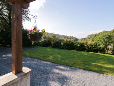 A garden with a hanging flower basket a grassy lawn and gravel path at Dalegarth Hall Farm Cottage 1 Boot near Eskdale Green