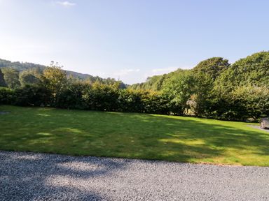A green lawn with gravel path and trees in the background at Dalegarth Hall Farm Cottage 1 Boot near Eskdale Green