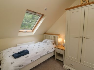 A bedroom with a single bed and folded towels on it a bedside table with a lamp and a wardrobe at Gelli Barn Near Llandeilo