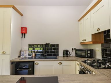 A kitchen with white cabinets black backsplash a black sink a kettle microwave and gas stove at Adipit Stables Buckland Brewer near Bideford
