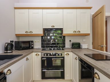A kitchen with white cabinets black appliances and a wooden countertop at Adipit Stables Buckland Brewer near Bideford