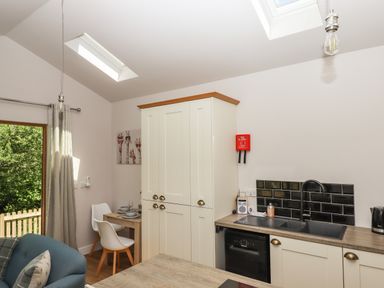 A kitchen area with cream cabinets a black sink and a small dining table with white chairs at Adipit Stables in Buckland Brewer near Bideford