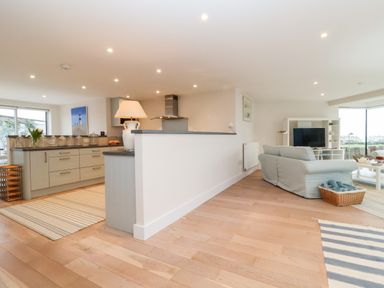 An open-plan kitchen and living room with a sofa and TV at Pebbles in Southwold