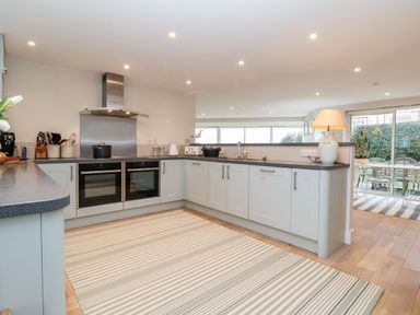 A kitchen with light cabinets dual ovens a striped rug and a lamp on the counter at Pebbles Southwold