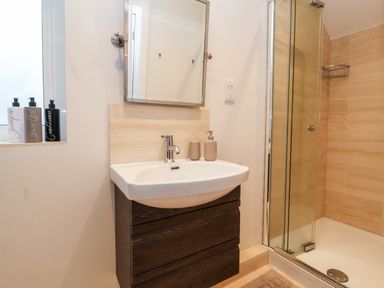 A bathroom with a sink cabinet mirror shower gel and a shower enclosure at Pebbles in Southwold