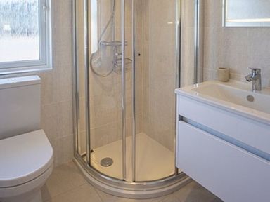 A bathroom with a shower enclosure a toilet and a sink unit at E19 The Warren in Abersoch