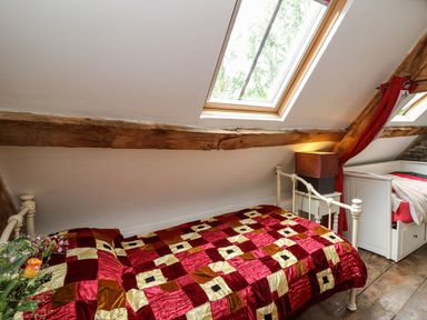 A bedroom with two single beds under skylight windows and wooden beams at Ty Fferm Hen in Talybont-on-Usk