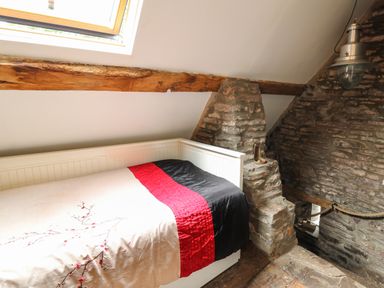 A small bedroom with a single bed under a skylight and exposed stone walls at Ty  Fferm Hen in Talybont-on-Usk