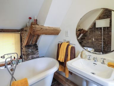 A bathroom with a white clawfoot bathtub sink and round mirror at Ty Fferm Hen in Talybont-on-Usk