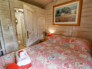 A bedroom with a bed covered in a quilted blanket and an open door showing a bathroom at Ty Bach Twt in Talybont-on-Usk