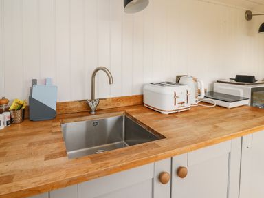 A kitchen countertop with a sink toaster kettle and microwave at Ty Olwyn Bach in Talybont-on-Usk