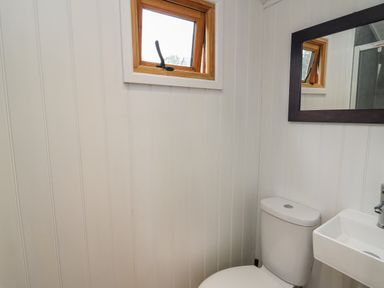 A bathroom with a toilet sink mirror and a small window with a wooden frame at Ty Olwyn Bach in Talybont-on-Usk
