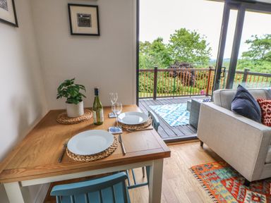 A dining table with two place settings next to a sliding door leading to a balcony with outdoor furniture at The Bothy Riding Hills Riding Mill near Corbridge