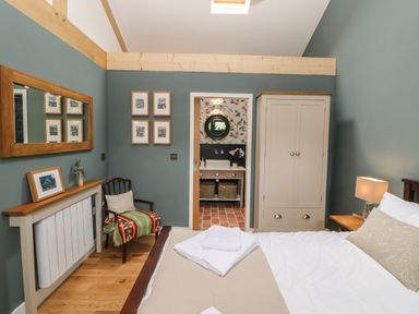 A bedroom with a bed a chair a wardrobe and an ensuite bathroom at The Bothy Riding Hills in Riding Mill near Corbridge