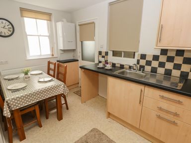 A kitchen with a dining table set for four and a sink with checkered backsplash at Flat 1 in Tenby