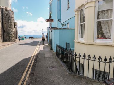 A street with a pedestrian walking towards the ocean and buildings on both sides at Flat 1 in Tenby