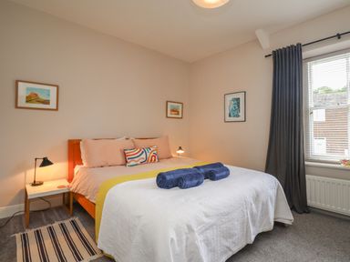 A bedroom with a double bed two bedside tables with lamps and a window with dark curtains at White Feathers in Alnwick
