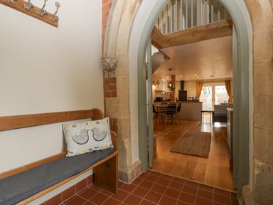 A hallway with a wooden bench and hooks leading to a dining area and kitchen at The Old Chapel in Dorstone near Hay-on-Wye