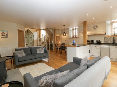 An open plan living area with two gray sofas a dining table and kitchen at The Old Chapel in Dorstone near Hay-on-Wye