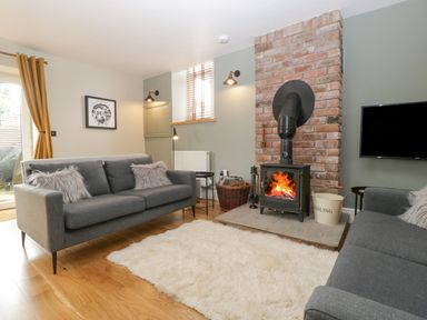 A living room with gray sofas a fireplace and a fluffy white rug at The Old Chapel in Dorstone near Hay-on-Wye