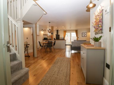 An open living space with staircase dining table chairs sideboard and sofa at The Old Chapel in Dorstone near Hay-on-Wye