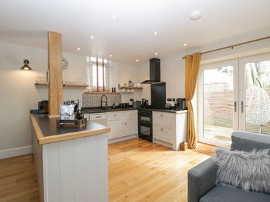 A kitchen with wooden floor cabinets a black stove and oven a dining counter and glass doors leading outside at The Old Chapel in Dorstone near Hay-on-Wye
