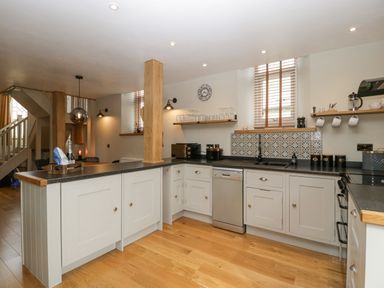 A kitchen with white cabinets wooden floor and black countertops at The Old Chapel in Dorstone near Hay-on-Wye