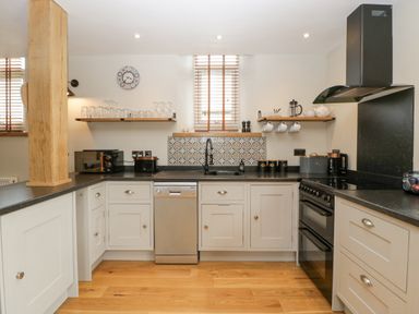 A kitchen with white cabinets black countertops a stainless steel dishwasher and stove at The Old Chapel in Dorstone near Hay-on-Wye