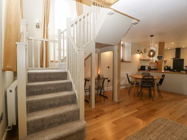 A staircase with carpet leading to an open plan dining area with a round table and chairs at The Old Chapel in Dorstone near Hay-on-Wye