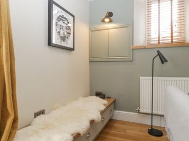 A corner with a bench covered by a white fur throw near a window with wooden blinds and a black floor lamp at The Old Chapel in Dorstone near Hay-on-Wye