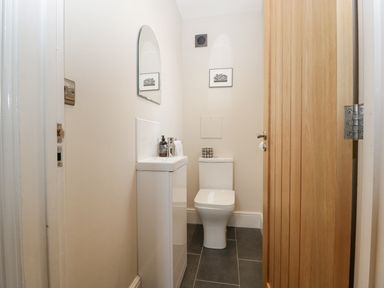 A small bathroom with a toilet sink mirror and wooden door at The Old Chapel in Dorstone near Hay-on-Wye