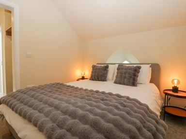 A bedroom with a bed with gray pillows and blanket and two bedside tables with lamps at The Old Chapel in Dorstone near Hay-on-Wye