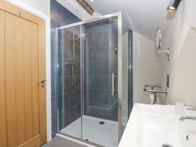 A bathroom with a glass shower enclosure wooden door and a white sink at The Old Chapel in Dorstone near Hay-on-Wye