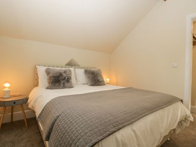 A bedroom with a bed grey blanket two furry pillows two round bedside tables with lamps at The Old Chapel in Dorstone near Hay-on-Wye