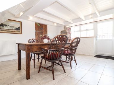A dining area with a wooden table and four chairs beside a door with windows at The Barn at Trevothen Farm in Coverack