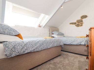 A bedroom with two single beds under a sloped ceiling at The Barn at Trevothen Farm in Coverack
