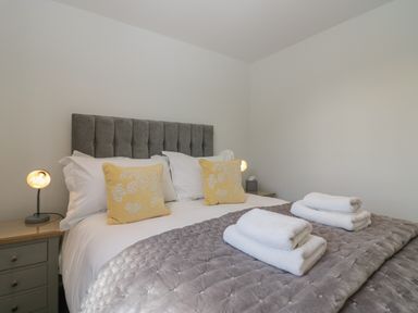 A bed with yellow pillows white towels and bedside tables with lamps at Betty's Loft in Hawkshead