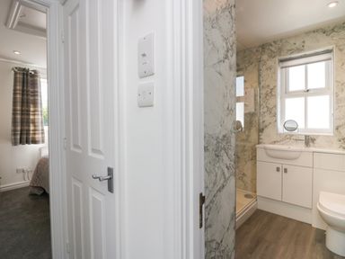 A hallway with a partially open door leading to a bedroom and an adjacent bathroom with a shower vanity and toilet at Betty's Loft in Hawkshead