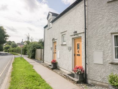 A exterior view of a white house with wooden doors and flower pots at Bettys Loft in Hawkshead