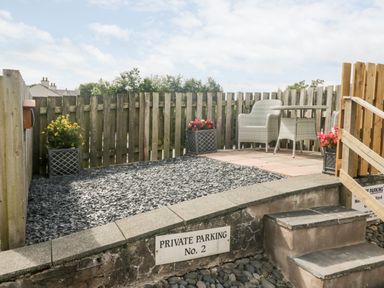 A small outdoor area with a wooden fence chairs, a table, and flower pots at Betty's Loft in Hawkshead