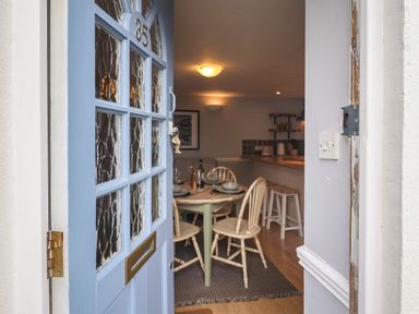 An open blue front door showing a dining area with a table set for four at Braiders Rest in Bridport