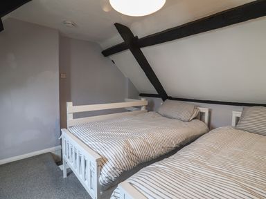A bedroom with two single beds with striped bedding and exposed wooden beams at Braiders Rest in Bridport