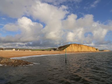 A beach with cliffs and buildings near the shore at Braiders Rest in Bridport