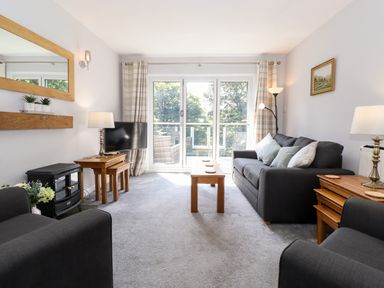 A living room with sofas tables TV and large windows at Fell View in Clappersgate near Ambleside
