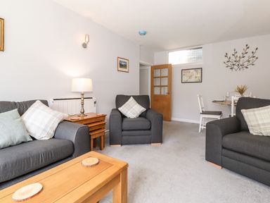 A living room with dark sofas a wooden coffee table and a dining table at Fell View Clappersgate near Ambleside