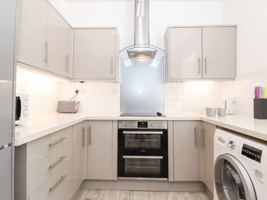 A kitchen with cabinets an oven a washing machine a microwave and a toaster at Fell View in Clappersgate near Ambleside
