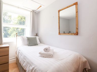 A bedroom with a single bed a mirror on the wall and a chest of drawers at Fell View in Clappersgate near Ambleside