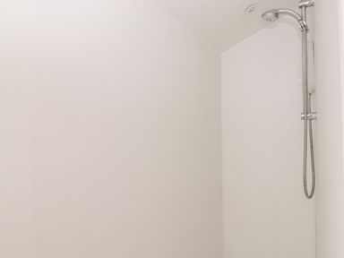 A shower area with a wall-mounted showerhead and hose at Fell View in Clappersgate near Ambleside