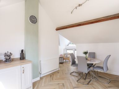 A dining area with round table and four chairs and a kitchen counter with utensils at Stabal Bach in Criccieth